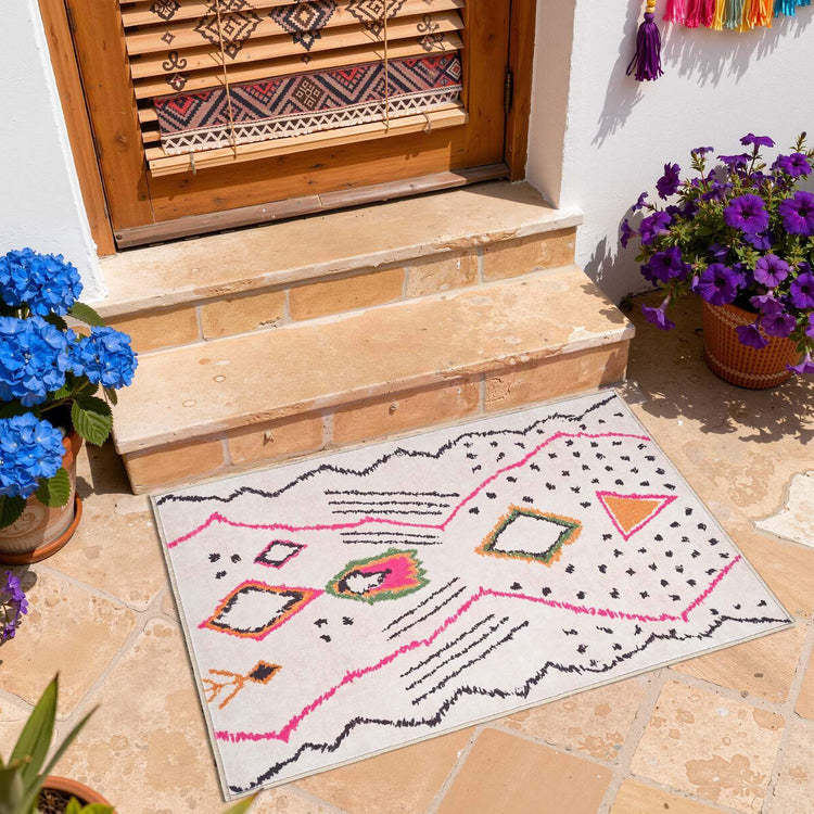 Colorful geometric patterned doormat on stone porch with blue and purple potted flowers