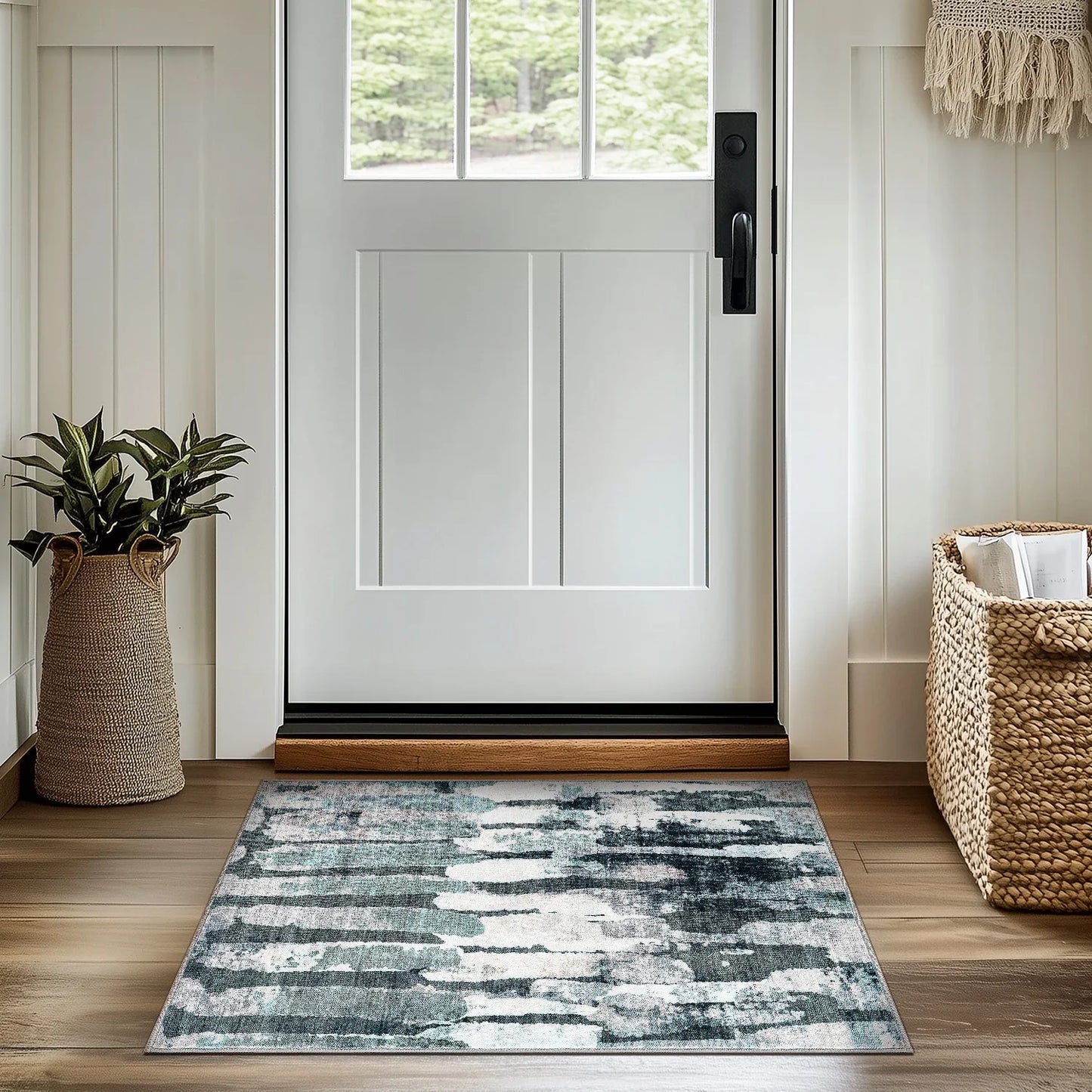 Modern entryway with white door, abstract blue-gray area rug on wooden floor, woven planter and basket