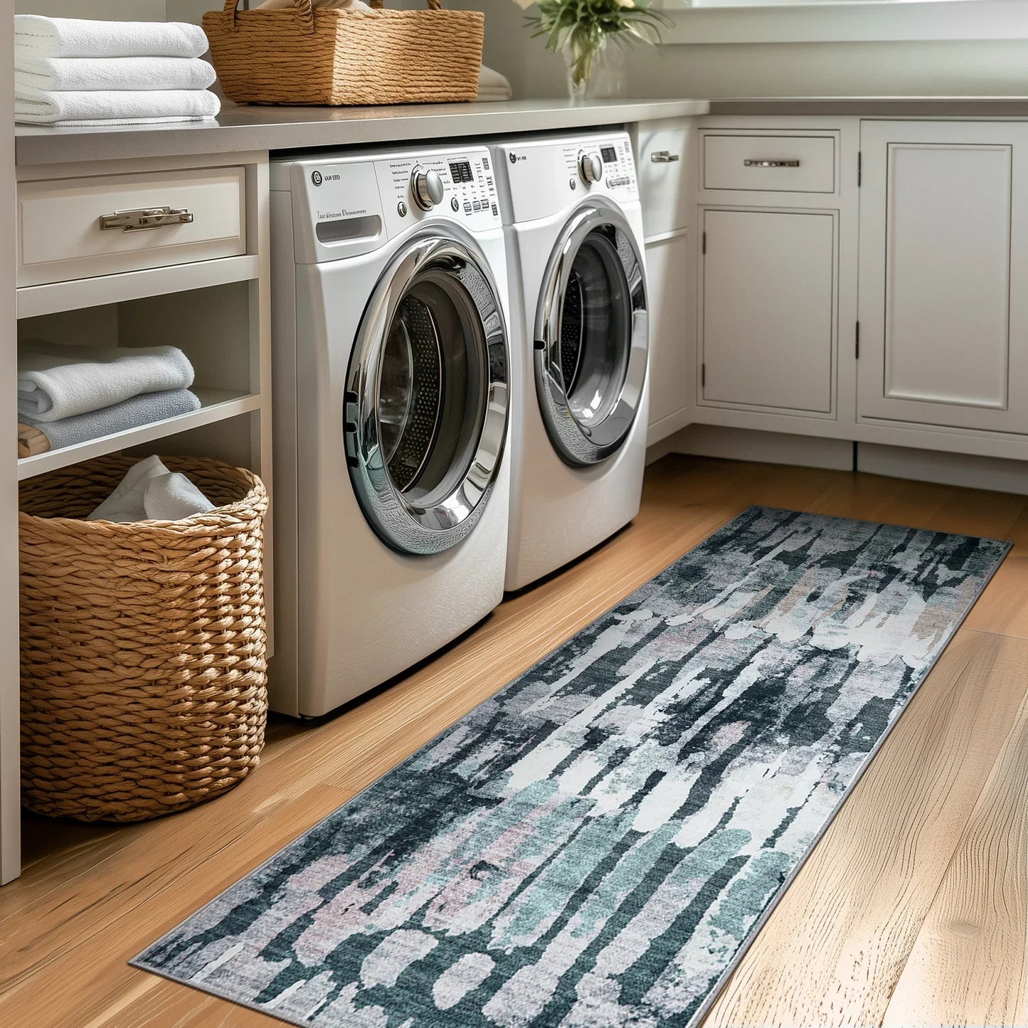 Modern laundry room with white front-load washer and dryer, woven baskets, folded towels, and patterned floor runner